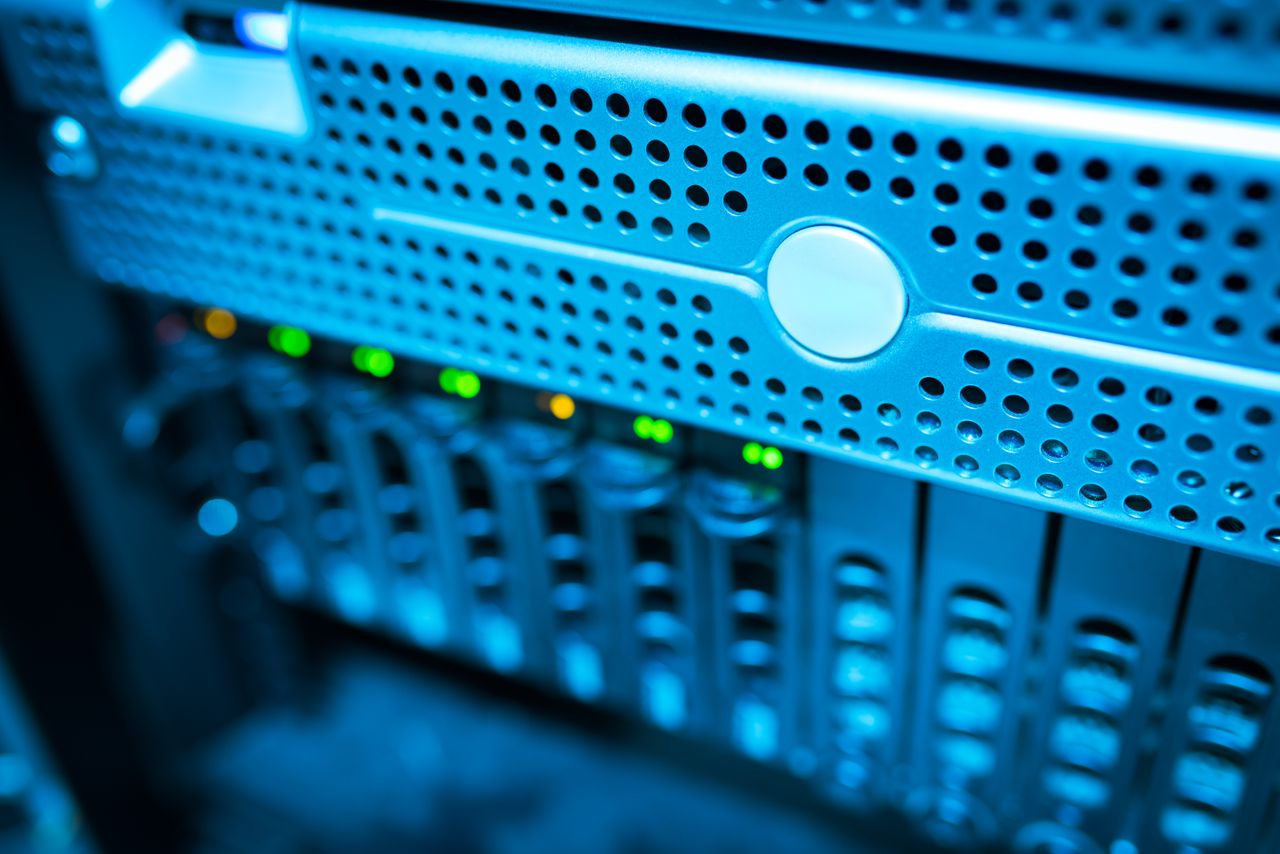 Focused view of a modern data server rack with blinking lights in a blue-lit environment.